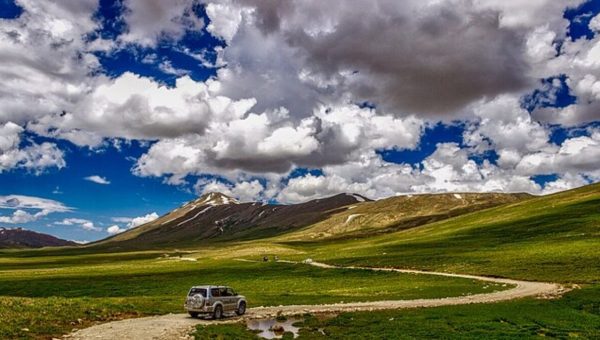 Golden evening light over the rolling grasslands of Deosai Plains with snow-capped peaks in the distance