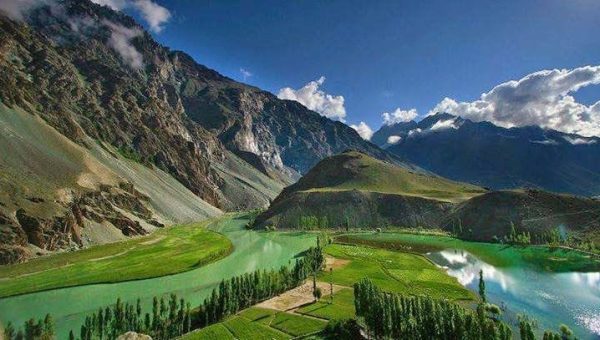 Phander Valley in Gilgit Baltistan, Pakistan with turquoise lake, lush green fields, and surrounding mountains